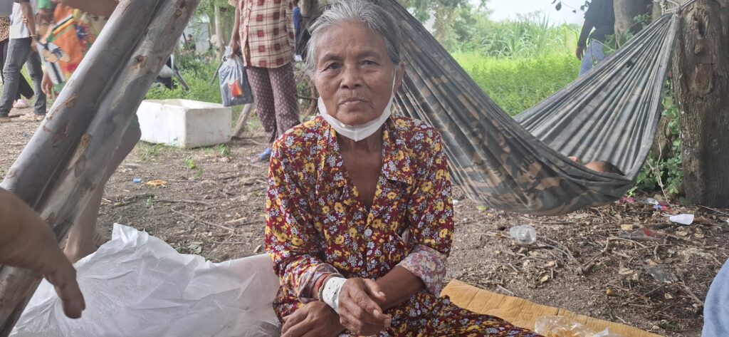Yon Vorn, 69, sits in front of a hammock at the Chouk Chey village campsite on Aug. 26, 2025 in Banteay Meanchey's Ou Bei Choan commune. Vorn said she injured her hand during the confrontation and wore a bandage. (Danielle Keeton-Olsen/Mekong Independent)