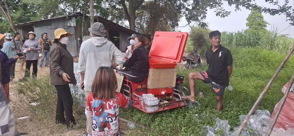 Civilians pass out free water bottles to visitors in Chouk Chey village on Aug. 26, 2025. Around one thousand people came to see where Cambodian civilians confronted Thai soldiers on Aug. 25, according to one village guard. (Danielle Keeton-Olsen/Mekong Independent)