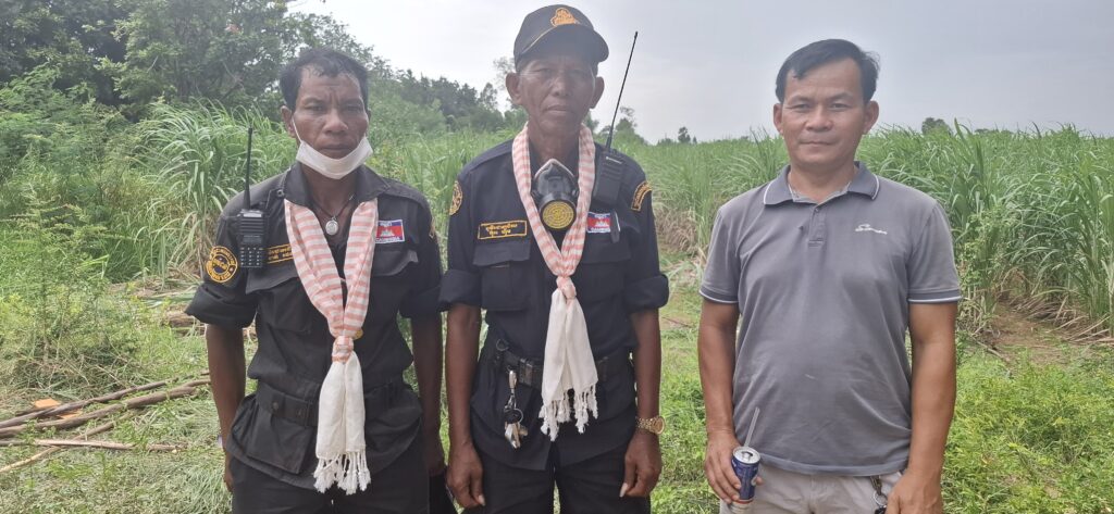 Village guards Than Theth (left), Ouk Him and a civilian, who gave his name as Sothea, stand in front of a sugar cane field where Cambodian civilians confronted Thai soldiers this week, in the disputed Chouk Chey village on Aug. 26, 2025. (Danielle Keeton-Olsen/Mekong Independent)