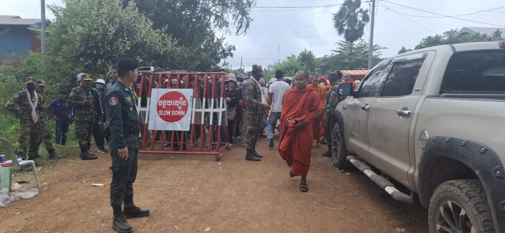 A monk walks past a border gate maintained by Cambodian military personnel in the disputed Chouk Chey village on Aug. 26, 2025. (Danielle Keeton-Olsen/Mekong Independent)