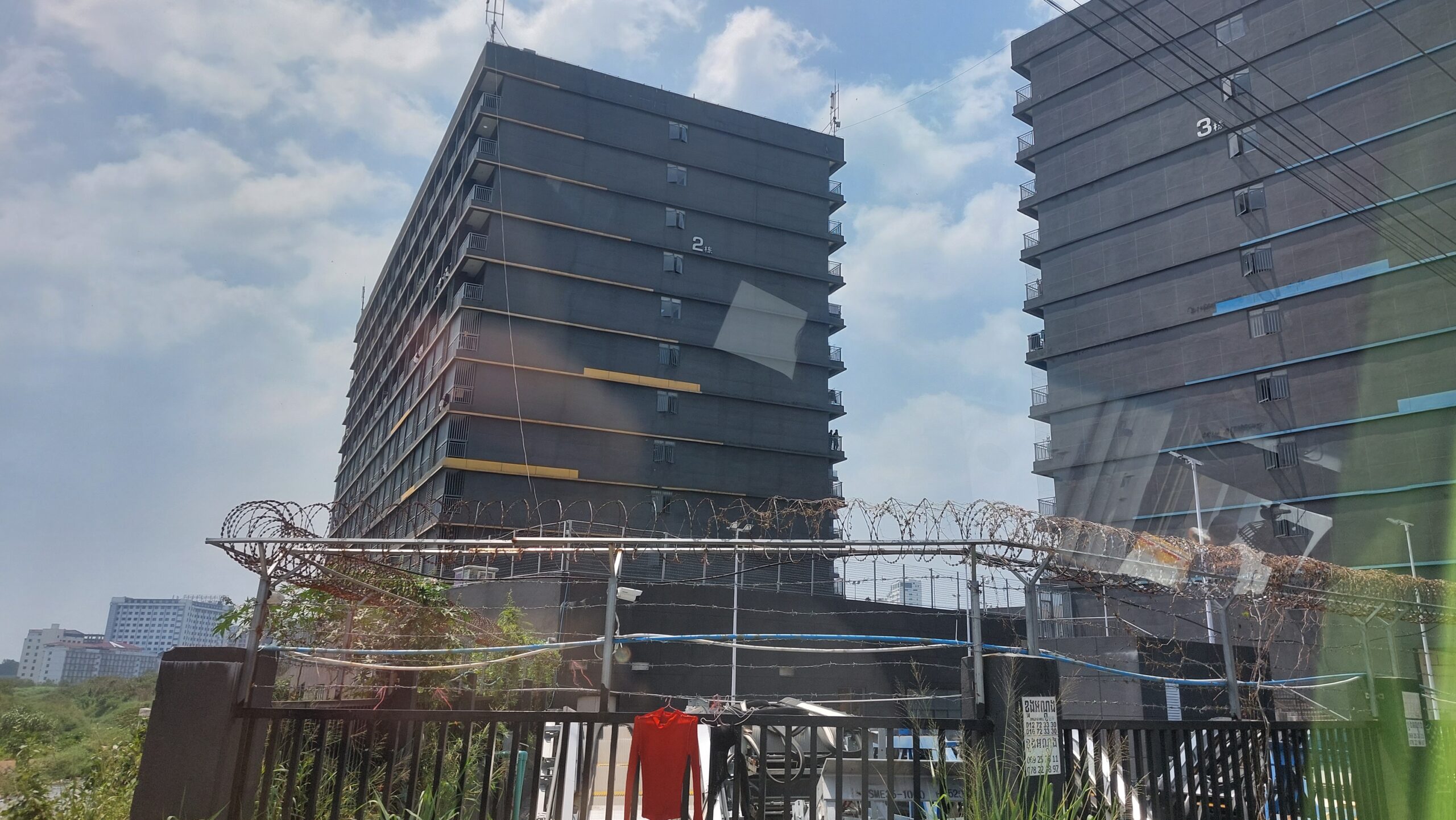 Two buildings and the barbed wire fence of Jin Bei 4 in Sihanoukville's Buon commune on March 4, 2023. (Danielle Keeton-Olsen/Mekong Independent/Creative Commons)