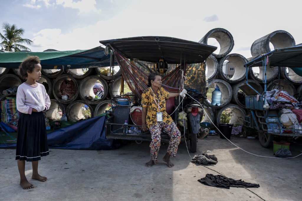 A woman leans on a motorized food cart packed with possessions, at a camp for civilians displaced by the border conflict with Thailand, in Cambodia's Siem Reap province on December 15, 2025. (Roun Ry/Mekong Independent)