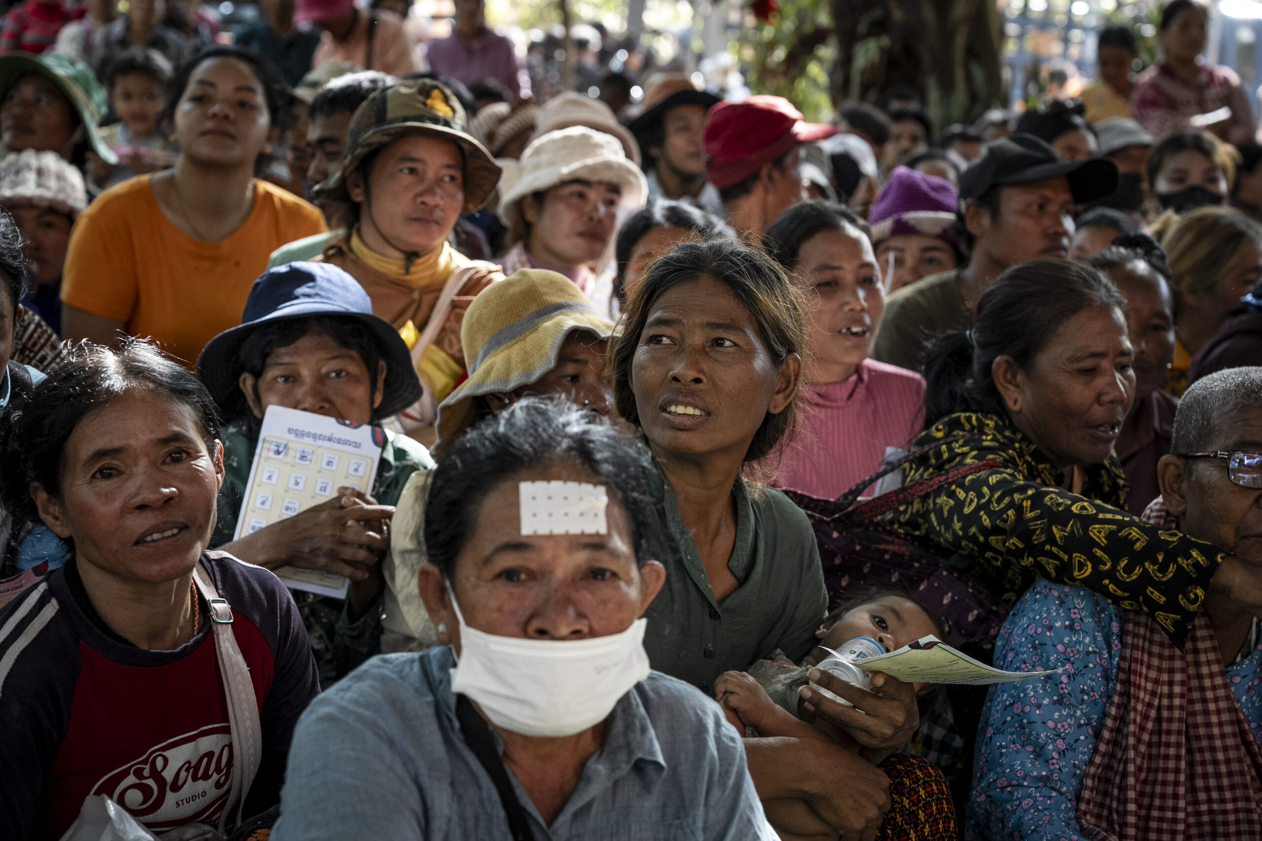Civilians hold tickets representing their families' place in the queue and wait among thousands for their numbers to be called during a donation distribution at the displaced persons camp in the Chroy Neang Ngourn pagoda in Cambodia’s Siem Reap province on December 15, 2025. (Roun Ry/Mekong Independent/Creative Commons)