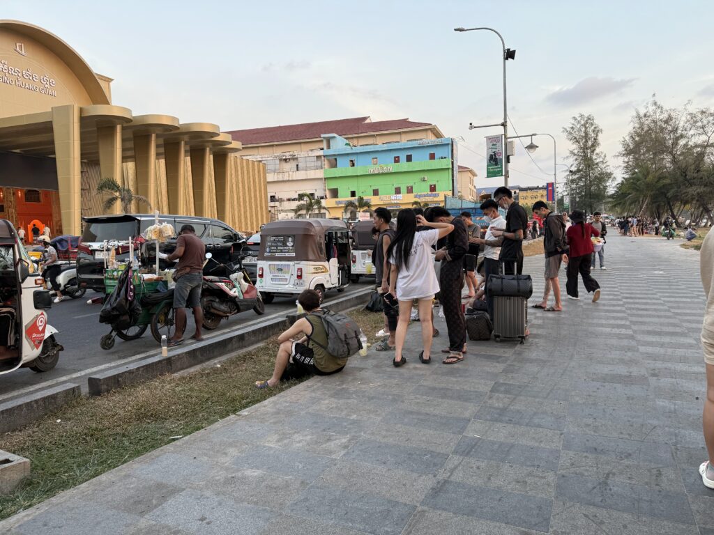 Foreigners stand with luggage in front of a beachside compound called Huangguan Chang Long Resort Hotel in Cambodia's Sihanoukville city, reportedly leaving ahead of a raid, on January 14, 2026. (Mech Dara/Mekong Independent)