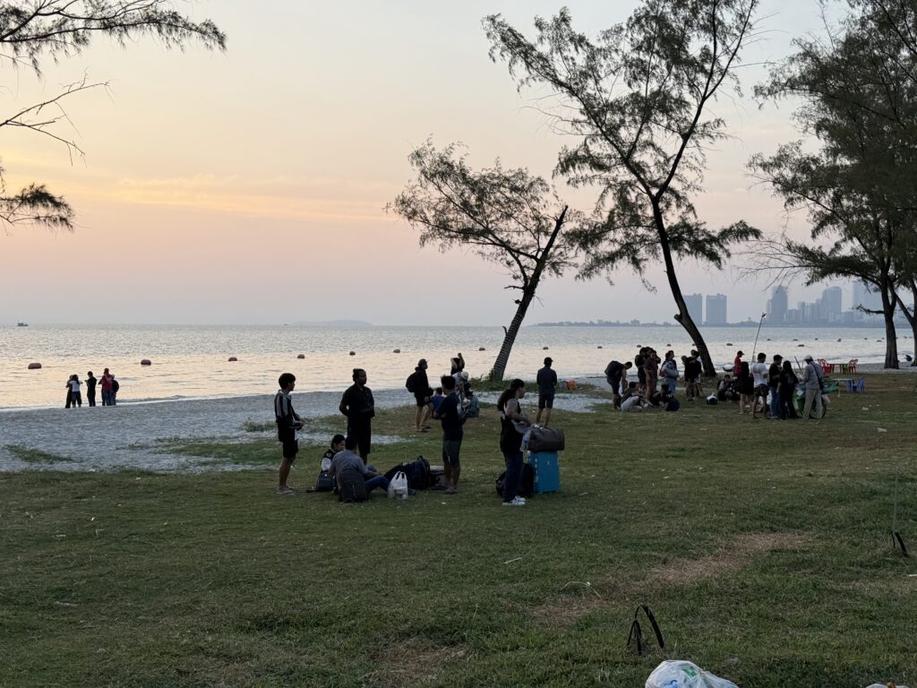 Foreigners take their luggage to the beach in front of a compound called Huangguan Chang Long Resort Hotel in Cambodia's Sihanoukville city, reportedly leaving ahead of a raid, on January 14, 2026. (Mech Dara/Mekong Independent)