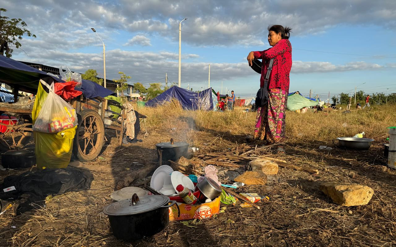 A woman carries a pot of rice to her cooking site in a camp for internally displaced persons in the Borey Huy Leng area of Cambodia's Banteay Meanchey province on December 17, 2025. (Mech Dara/Mekong Independent/Creative Commons)