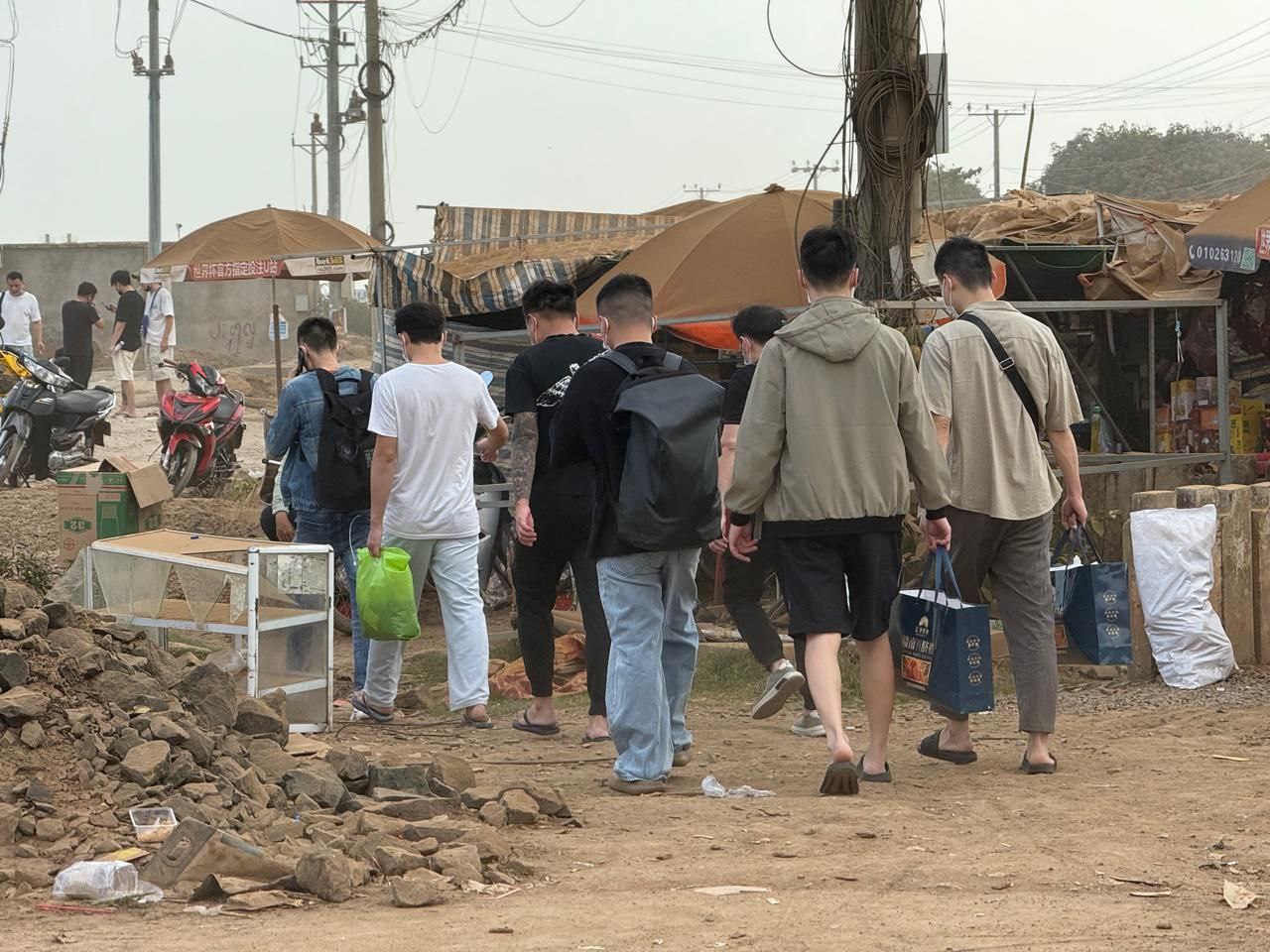 Foreign workers walk on dirt roads past construction to leave a scam complex in Cambodia's Tbong Khmum province, identified by Cyberscam Monitor as Rongxingdi Resort World, on January 17, 2026. (Mech Dara/Mekong Independent/Creative Commons)