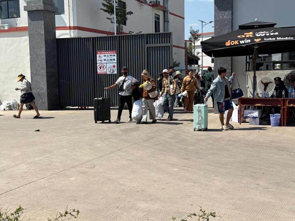 Workers cover their faces and carry their luggage out of the gate of A7 Park in Cambodia's Bavet city during a police raid on February 1, 2026. (Mech Dara/Mekong Independent)
