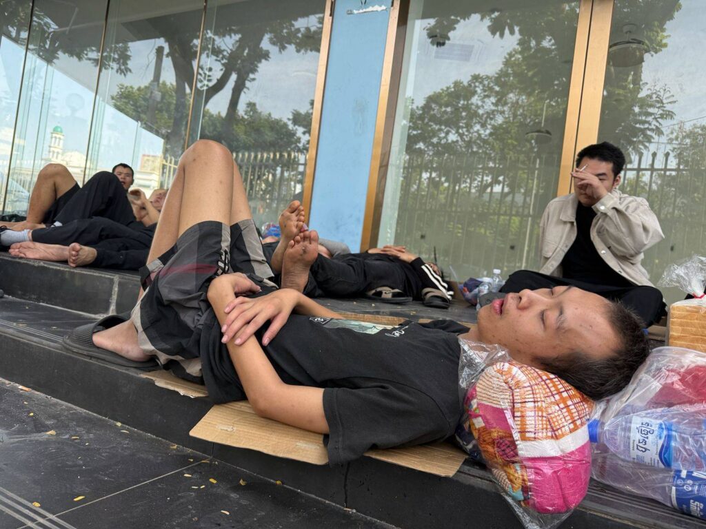 A group of men rest on the steps of a storefront across the street from the Chinese Embassy in Phnom Penh. (Mech Dara/Mekong Independent)