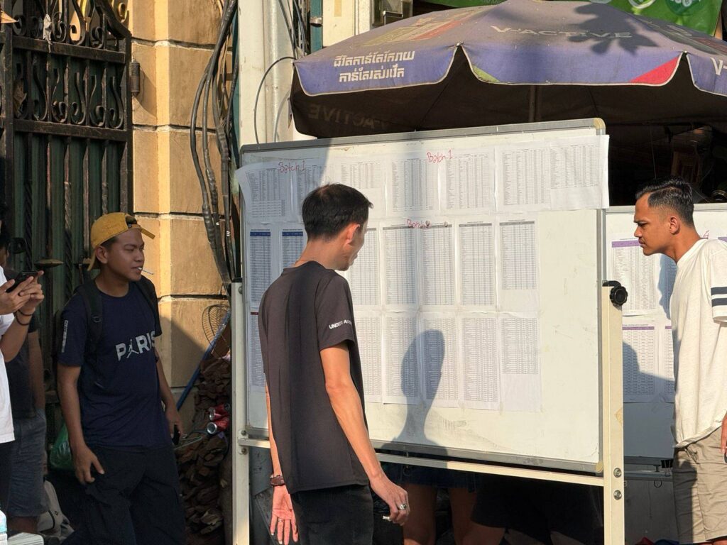 Indonesian citizens look at a list of names of exit visa recipients to leave Cambodia in front of the Indonesian Embassy in Phnom Penh on February 25, 2026. (Mech Dara/Mekong Independent)